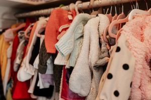 Closet rack filled with colorful children's clothing and sweaters hanging on hangers.