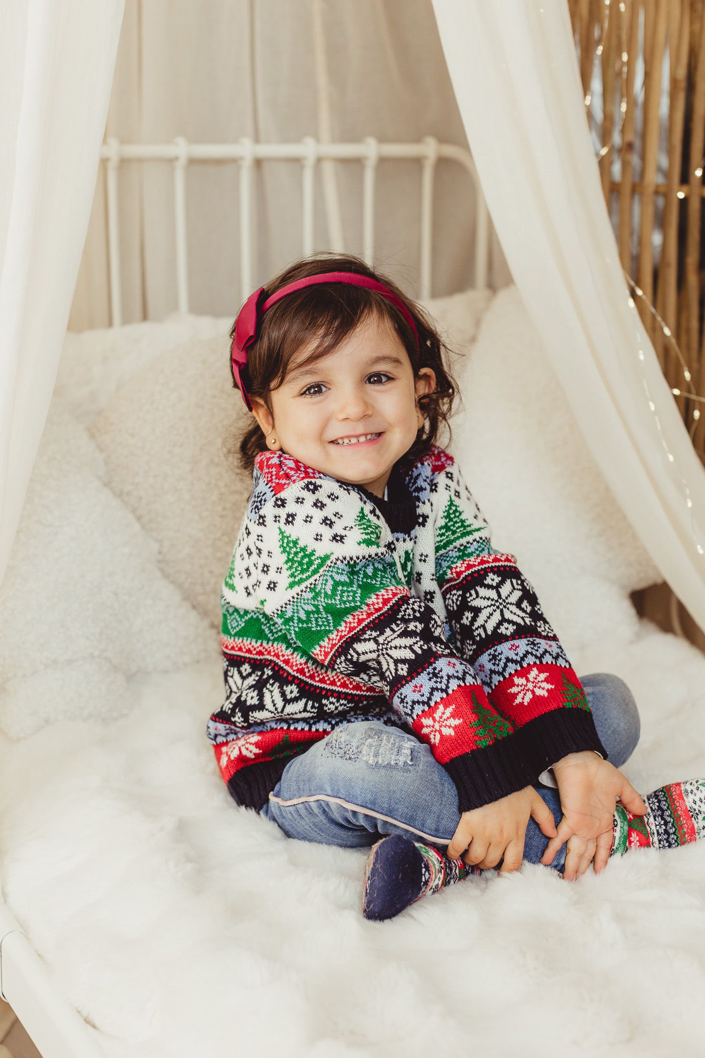 Winter themed photo session with child wearing festive sweater in snowy setting.