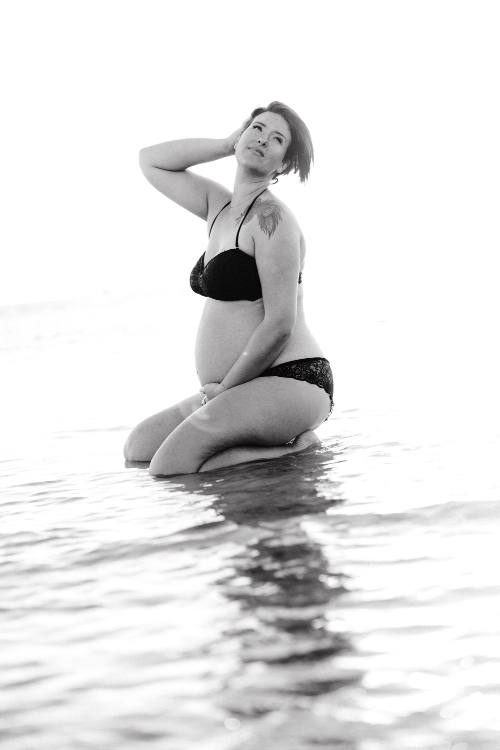 Black and white artistic portrait of a person posing gracefully in water with reflective ripples.