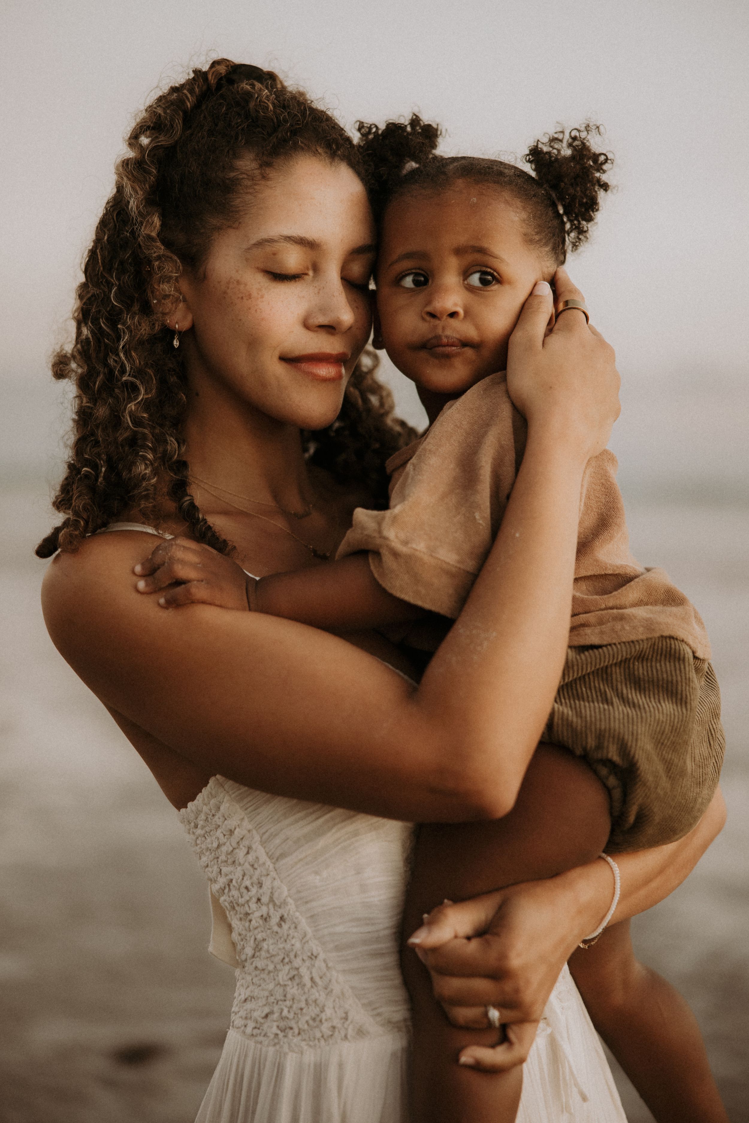 A tender embrace between parent and child on a cloudy day at the beach captured in a series of intimate photographs.