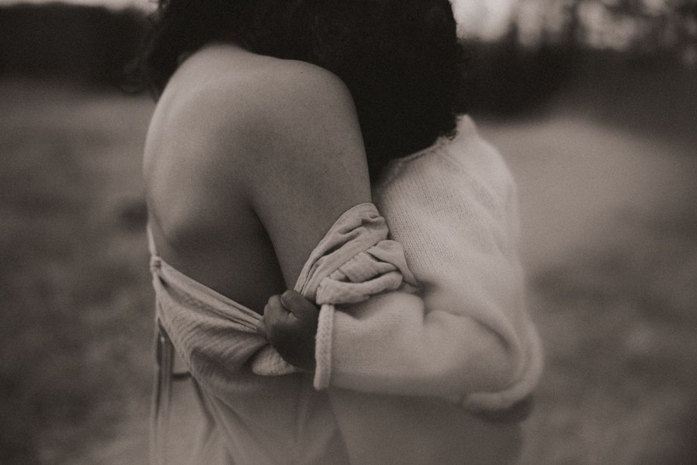 Black and white artistic photograph showing shoulders draped in delicate fabric with soft focus and romantic styling.