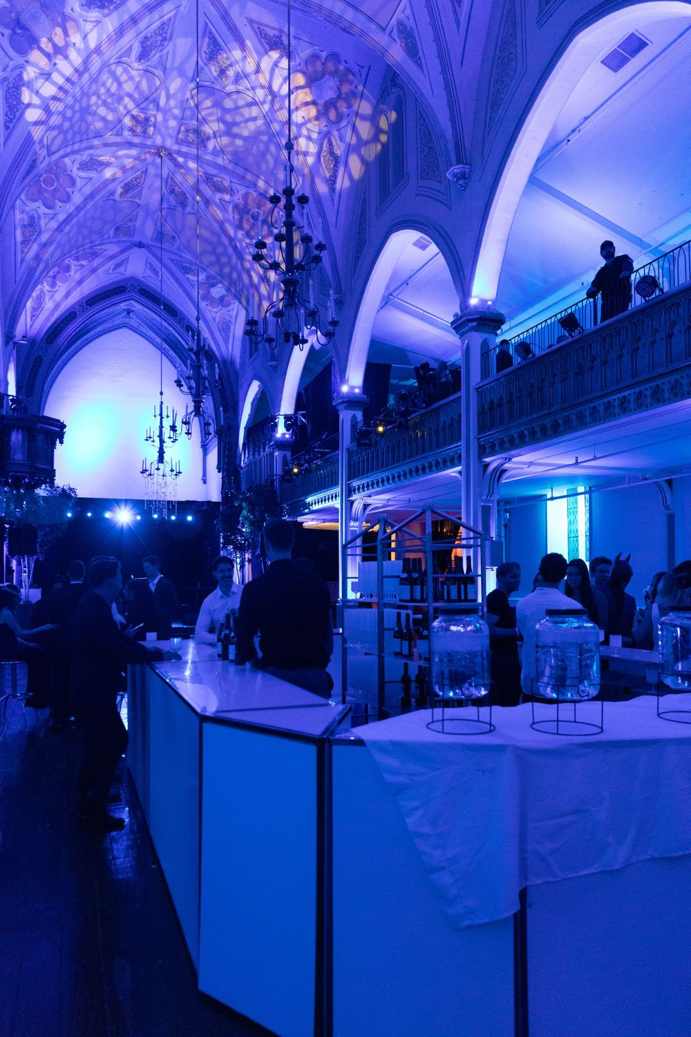 Elegant venue interior illuminated in blue lighting with vaulted ceilings and ornate architectural details.