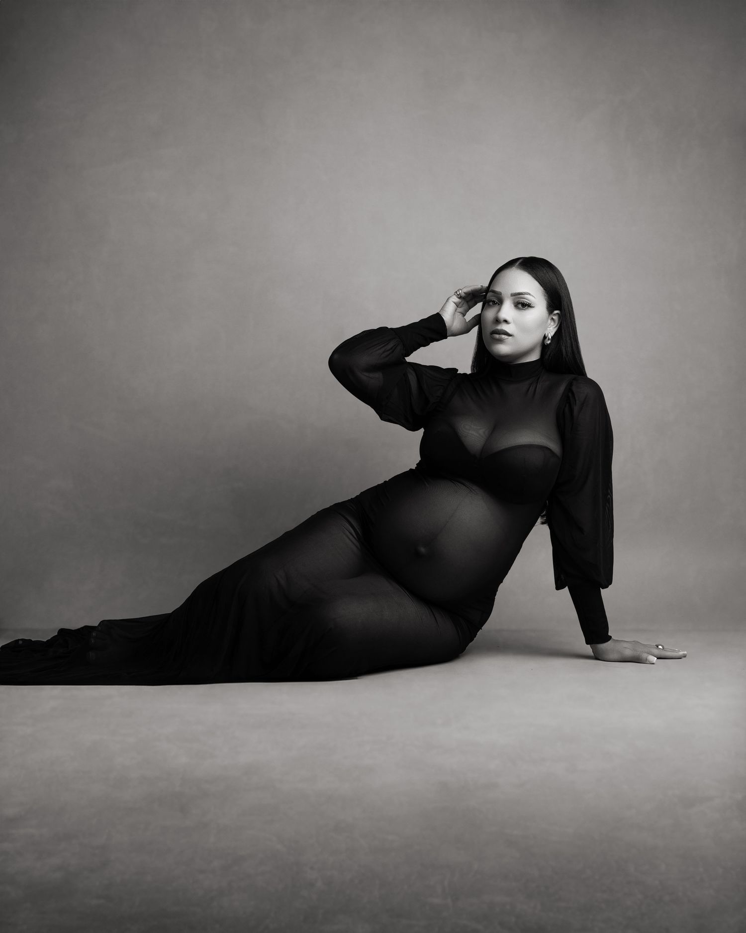 Minimalist black and white maternity photos showing artistic silhouettes against grey backdrop.