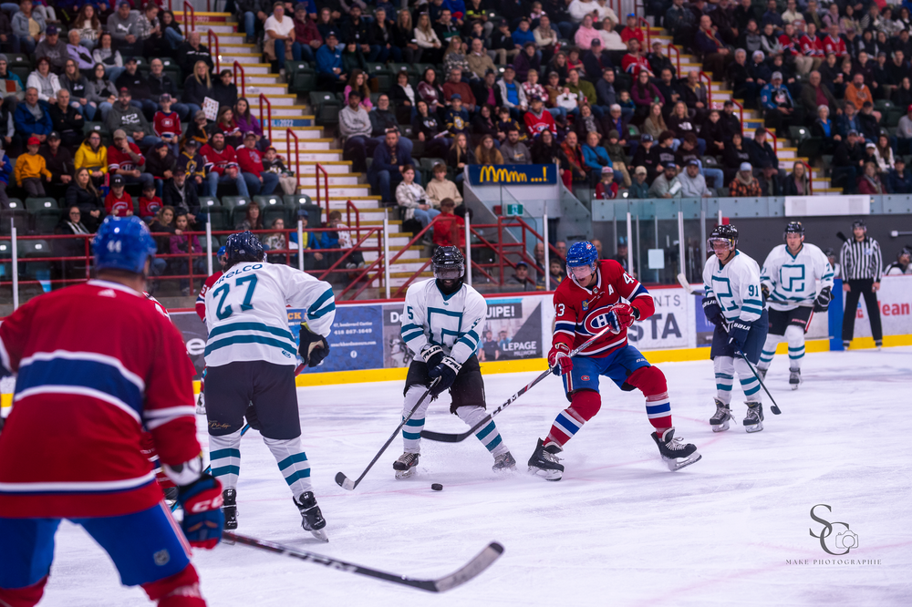Professional hockey teams compete in a crowded arena with fans watching from stadium seating.