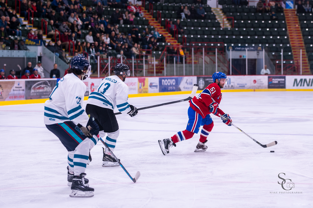 Hockey players from opposing teams battle for puck control during a competitive match on ice.