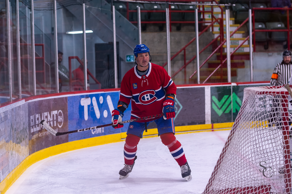 Hockey player in red Montreal Canadiens jersey positioned near the goal net during game.