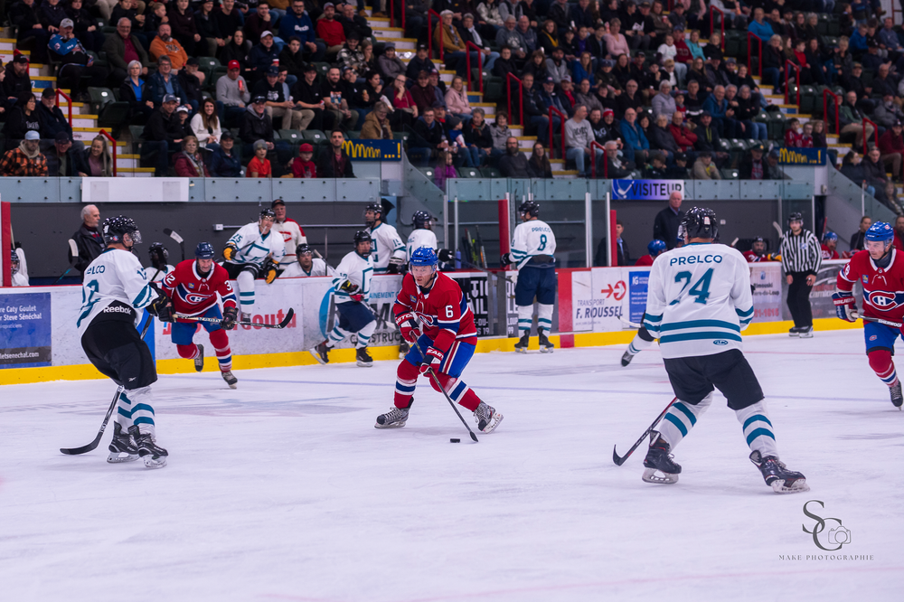 Ice hockey players from opposing teams battle for the puck during an intense match on the rink.