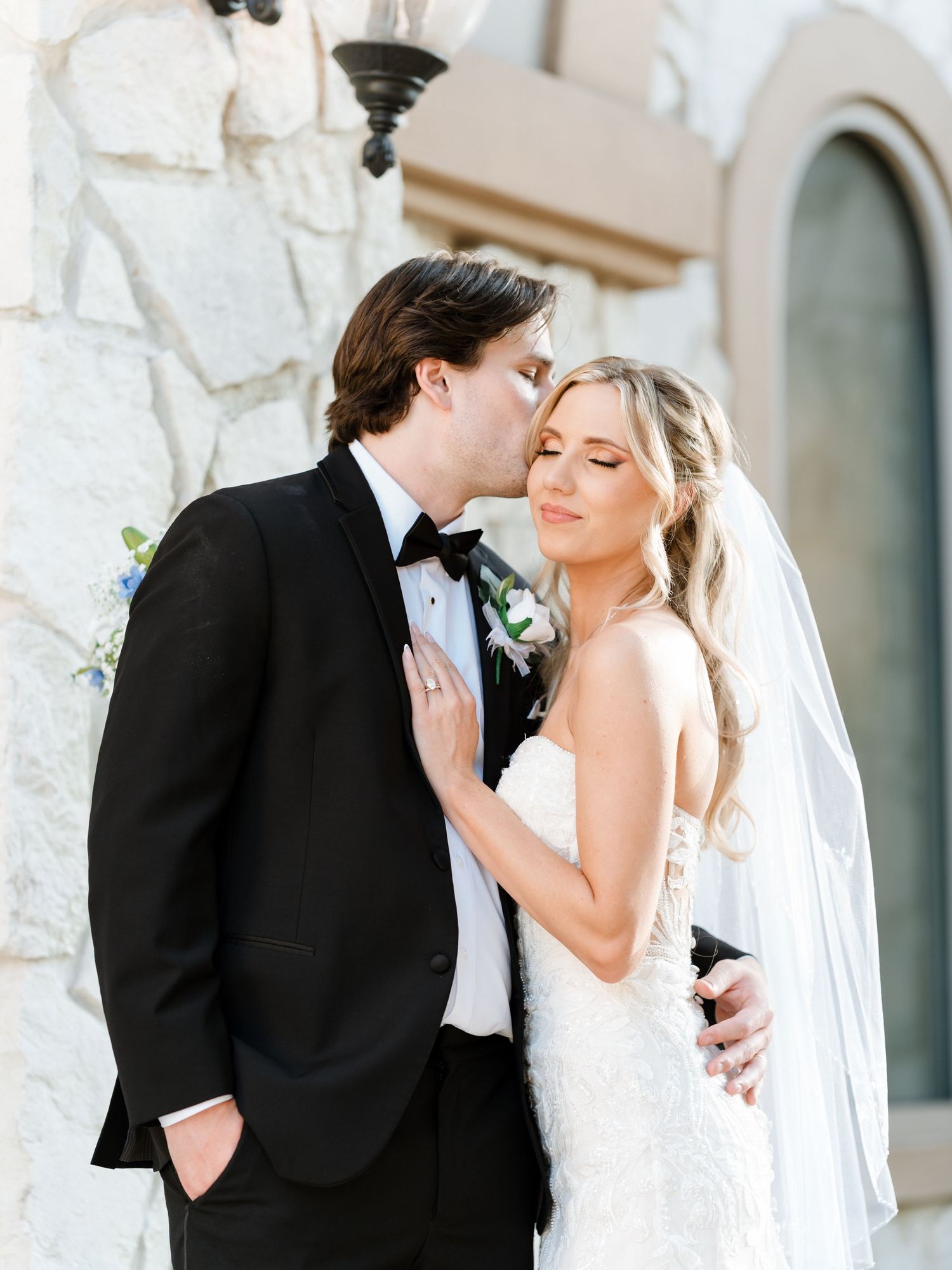 Newlywed couple pose outside modern building during wedding photography session.