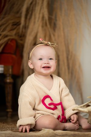 Sequence of photos showing a cream knit sweater with red details against a neutral background.