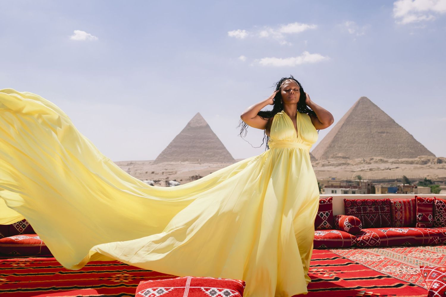 Yellow flowing dress catches desert breeze with Great Pyramids of Giza in background.