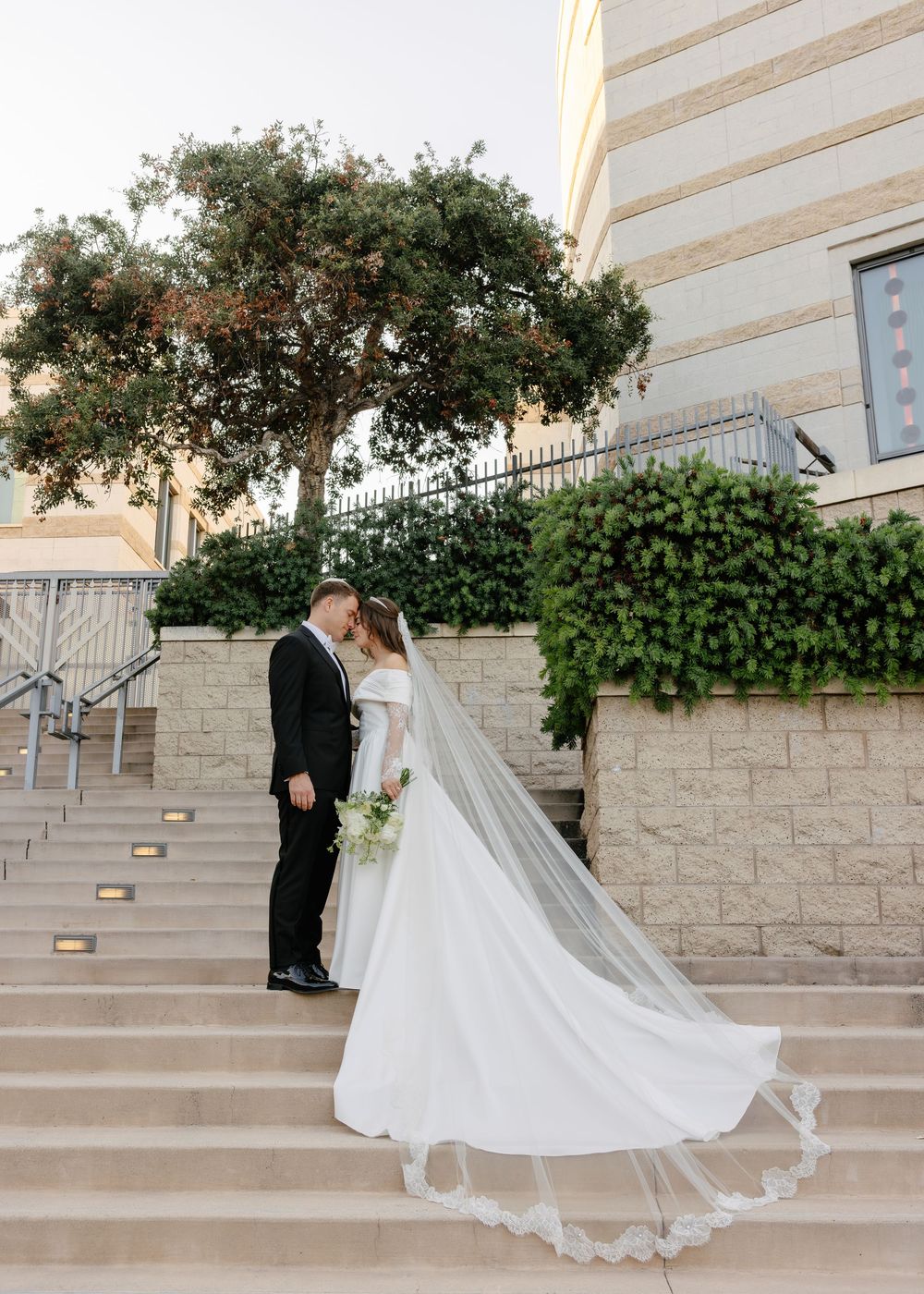 A series of wedding photos showing the train of a white wedding dress flowing elegantly down stone steps.