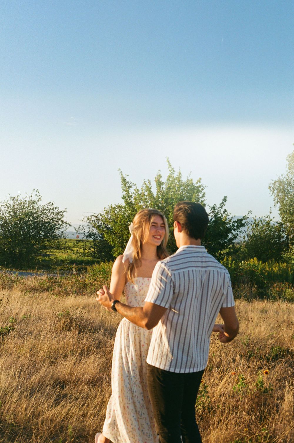 Dancing sequence captured in golden sunlight on coastal grassland.