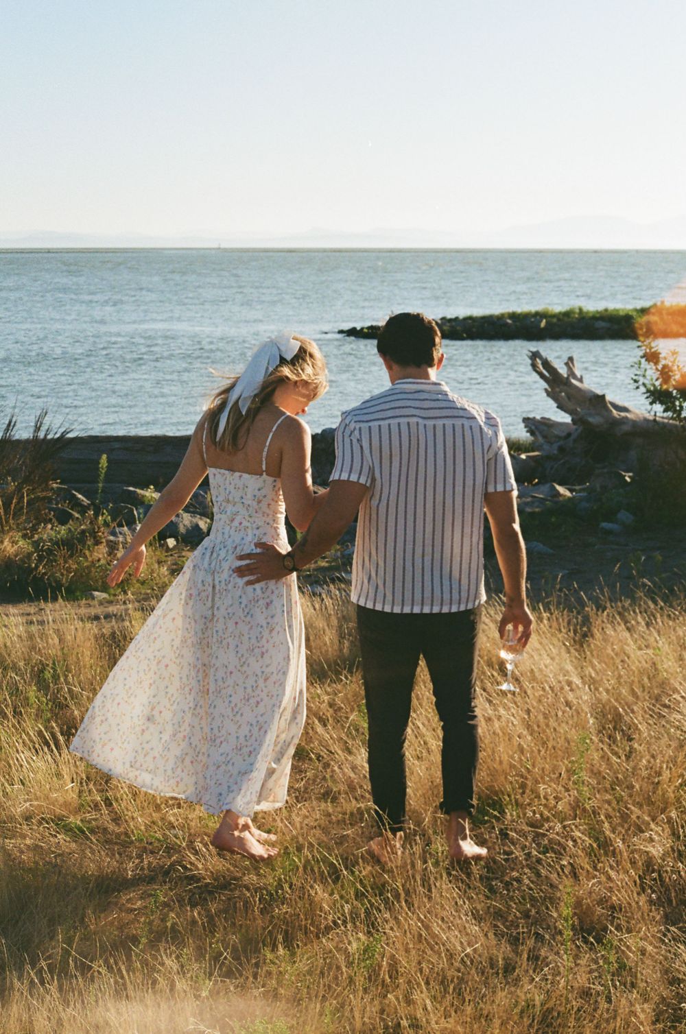 Couple walking together on coastal path during golden hour.