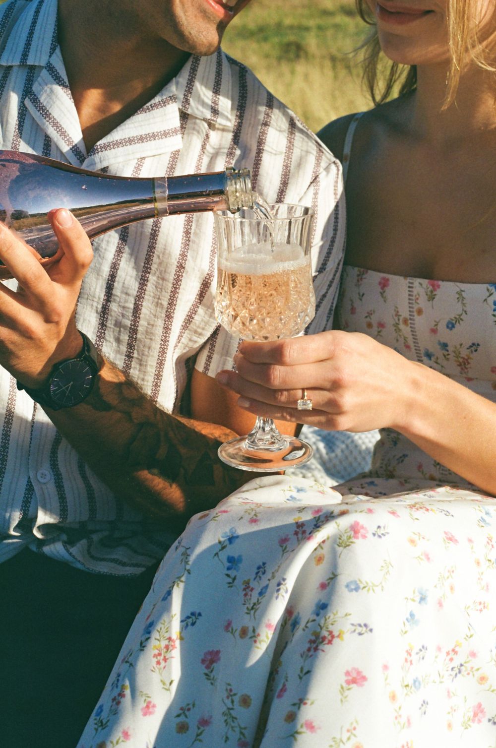 Close up of champagne being poured into vintage glasses during outdoor picnic.