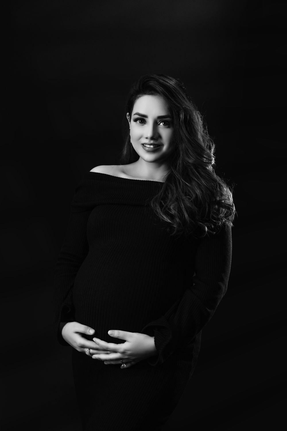 Classic black and white maternity portrait with elegant off-shoulder styling.