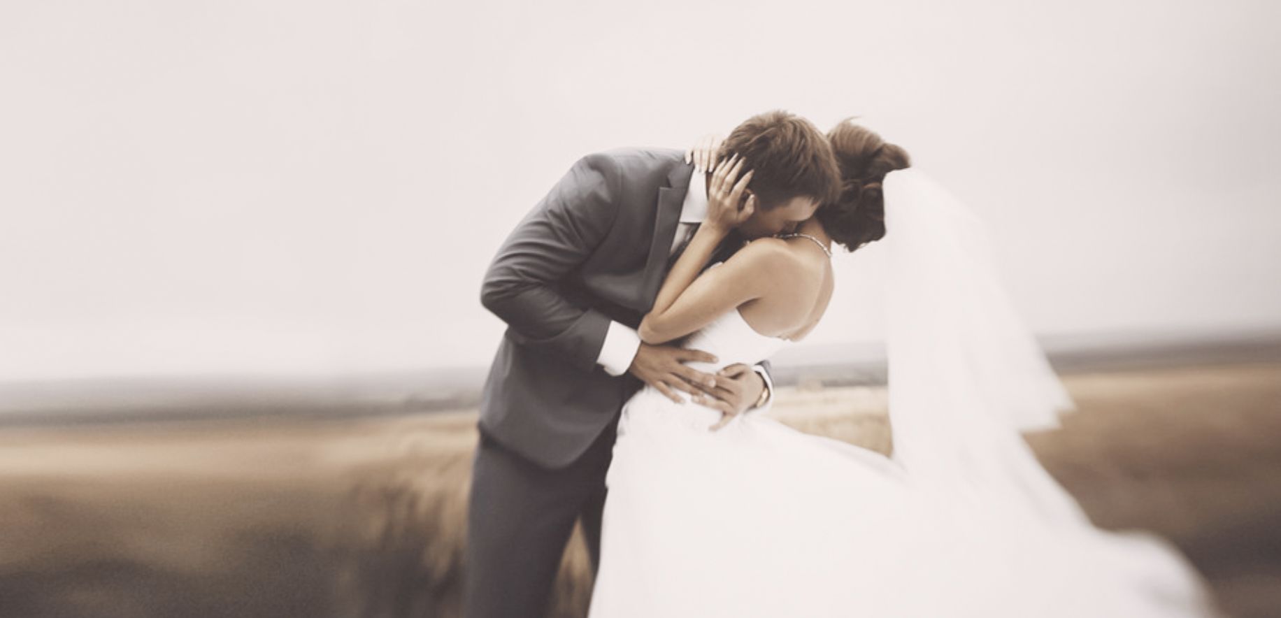 A romantic couple embracing on a misty beach with flowing white wedding dress in a dreamy atmosphere.