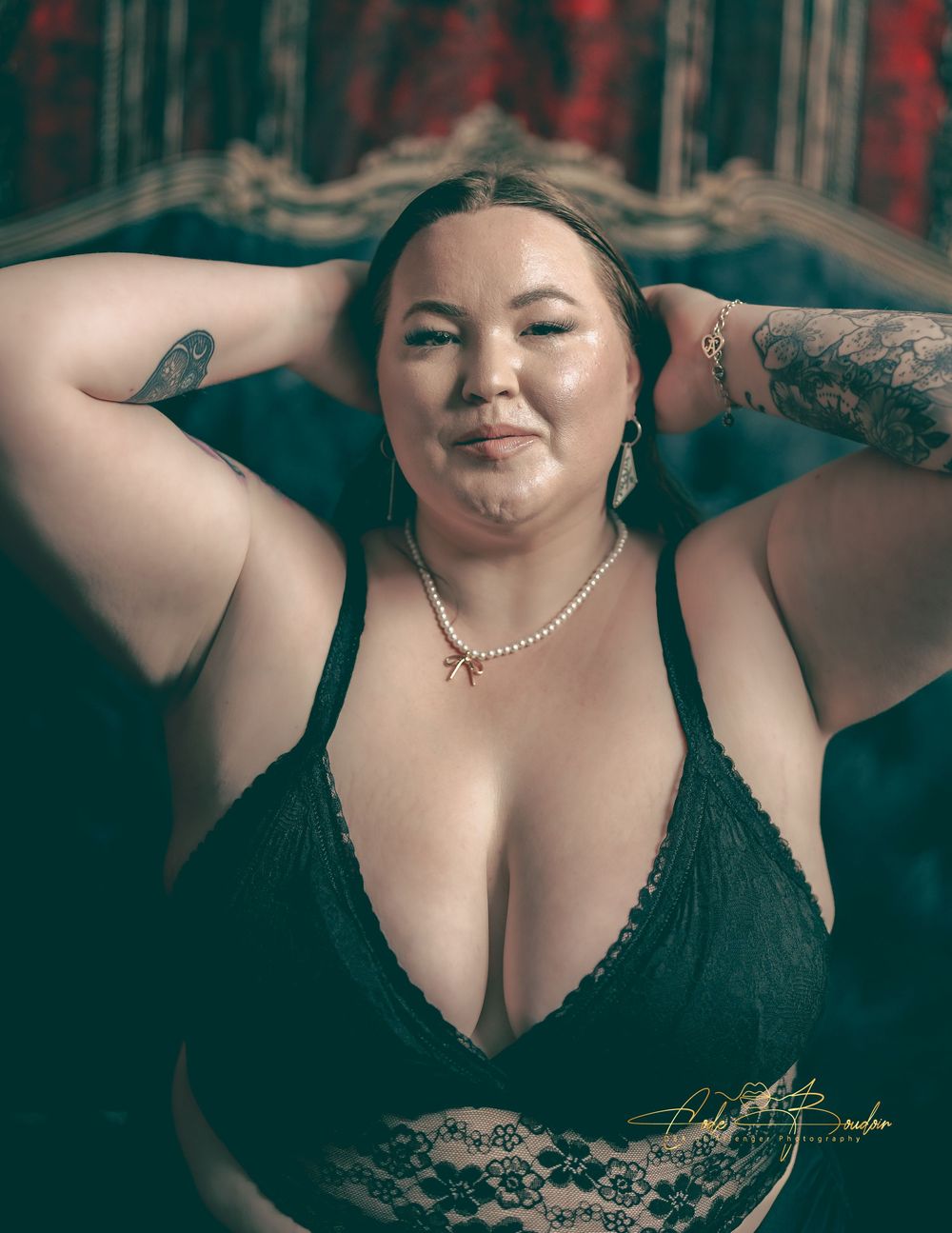 Woman in black lingerie, sitting on the bed wearing black lingerie for a boudoir photo shoot