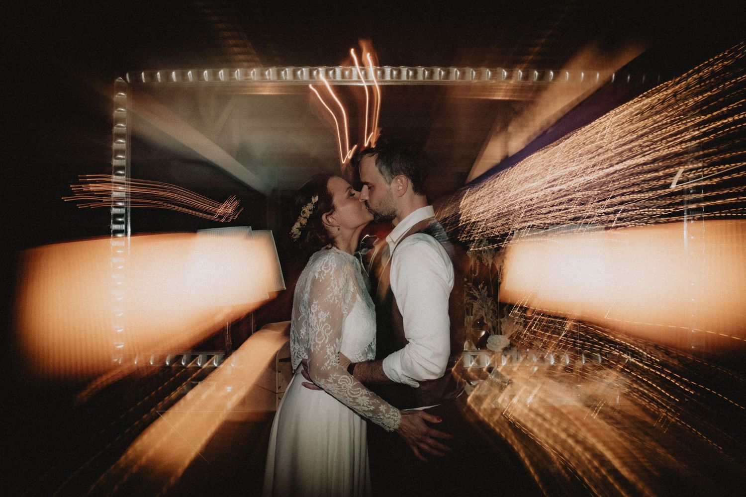 Bride and groom kissing with blurred lights behind them
