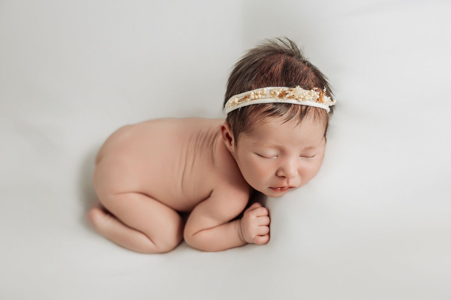 Momentos de calma en nuestra sesión newborn en Valencia, con el bebé arropado en una silla de mimbre estilo vintage, rodeado de cojines