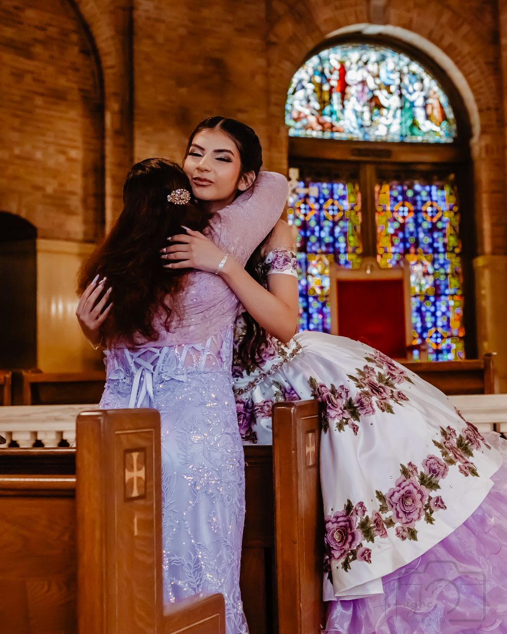 Emotional embrace captured in a church with stained glass windows and purple floral ball gown.Quinceanera