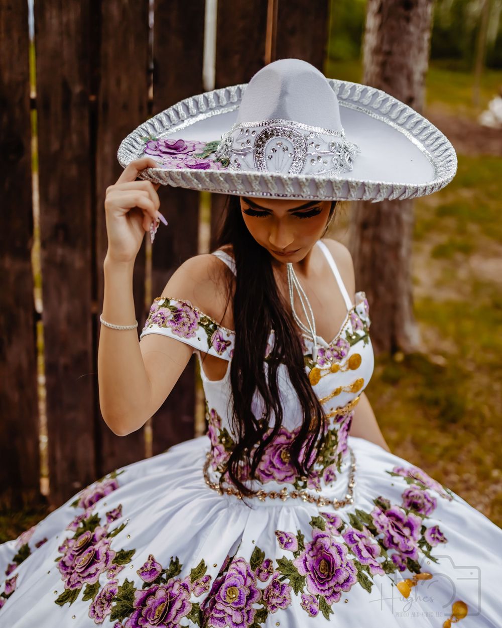 Elegant quinceañera dress with floral embroidery paired with traditional white sombrero.