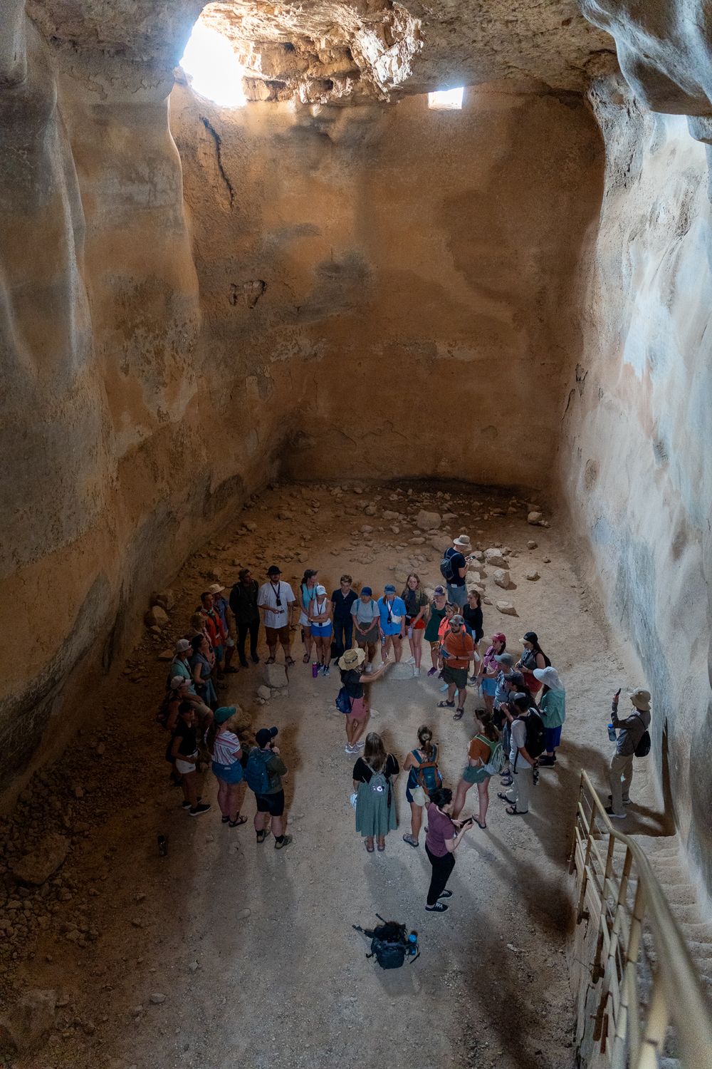 Historic cave chamber filled with tourists viewing ancient underground architecture.