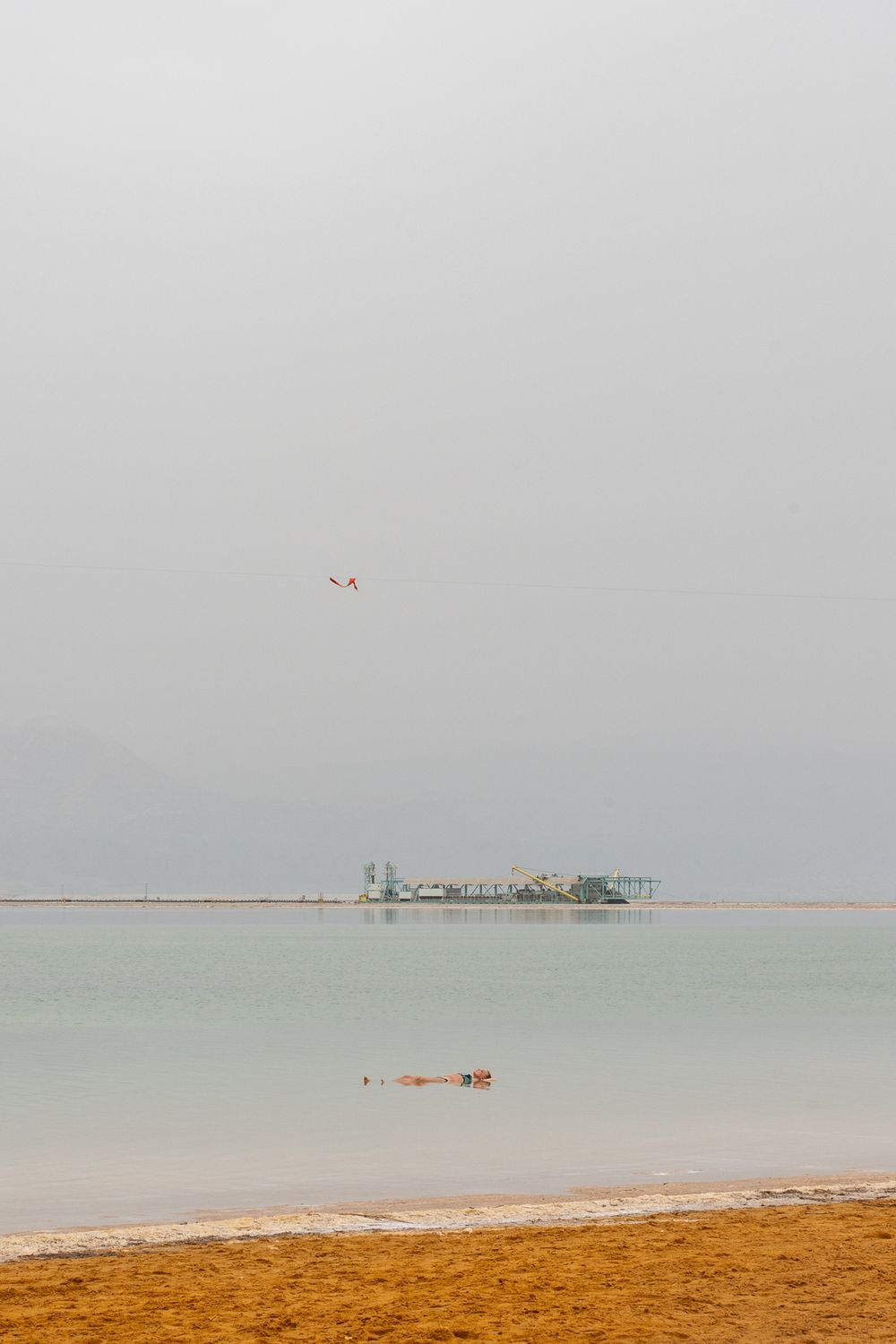 Tranquil beach scene with turquoise waters and sandy shore under overcast skies.