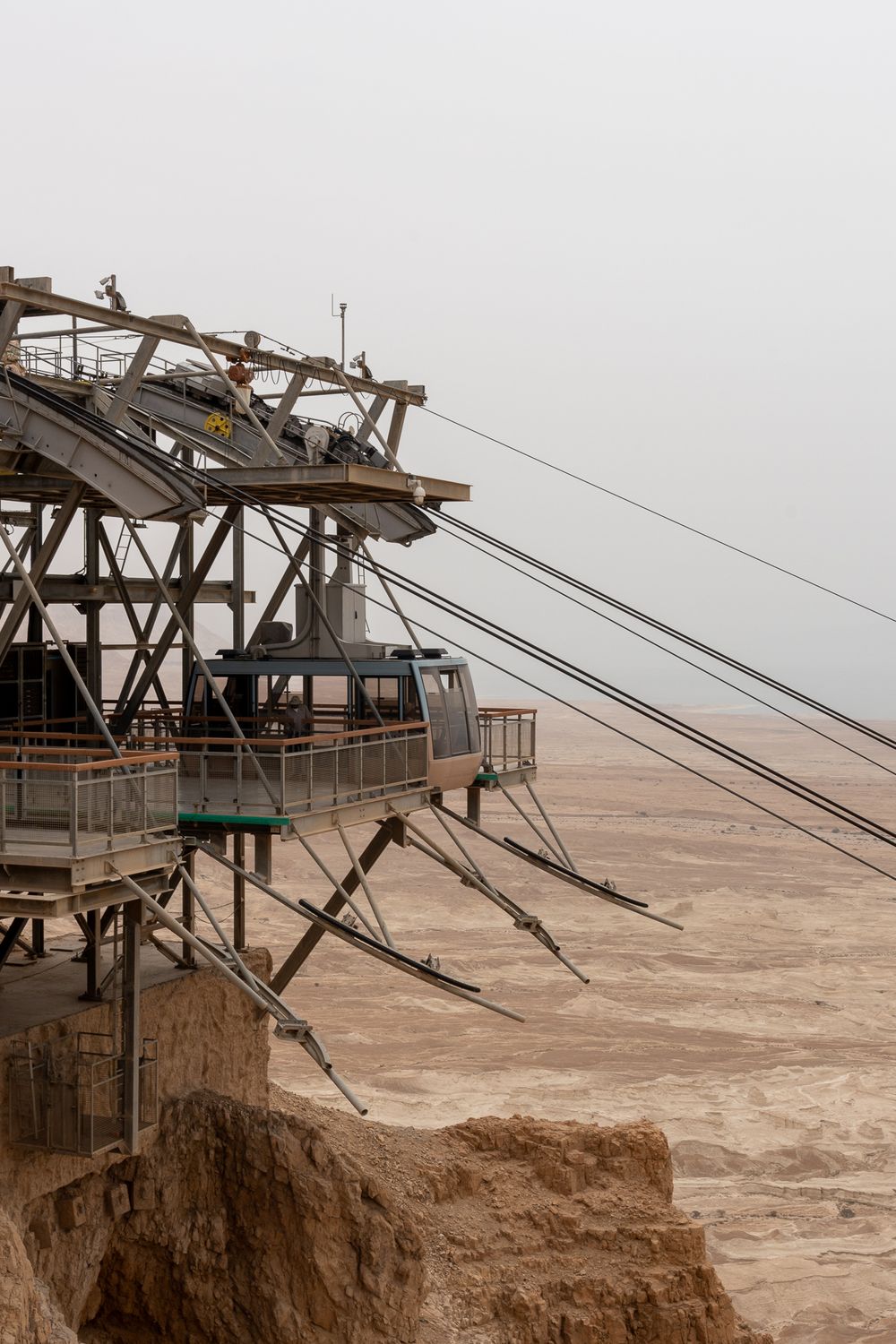 Cable car station perched on edge of desert cliff with support cables extending outward.