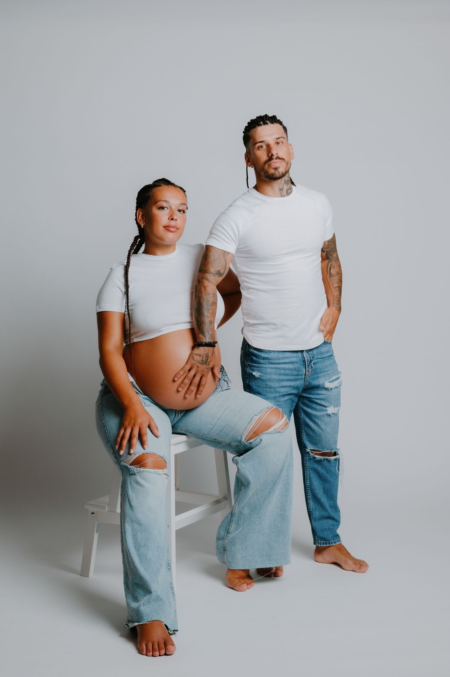 Dramatic black and white family maternity portrait with child against dark backdrop.