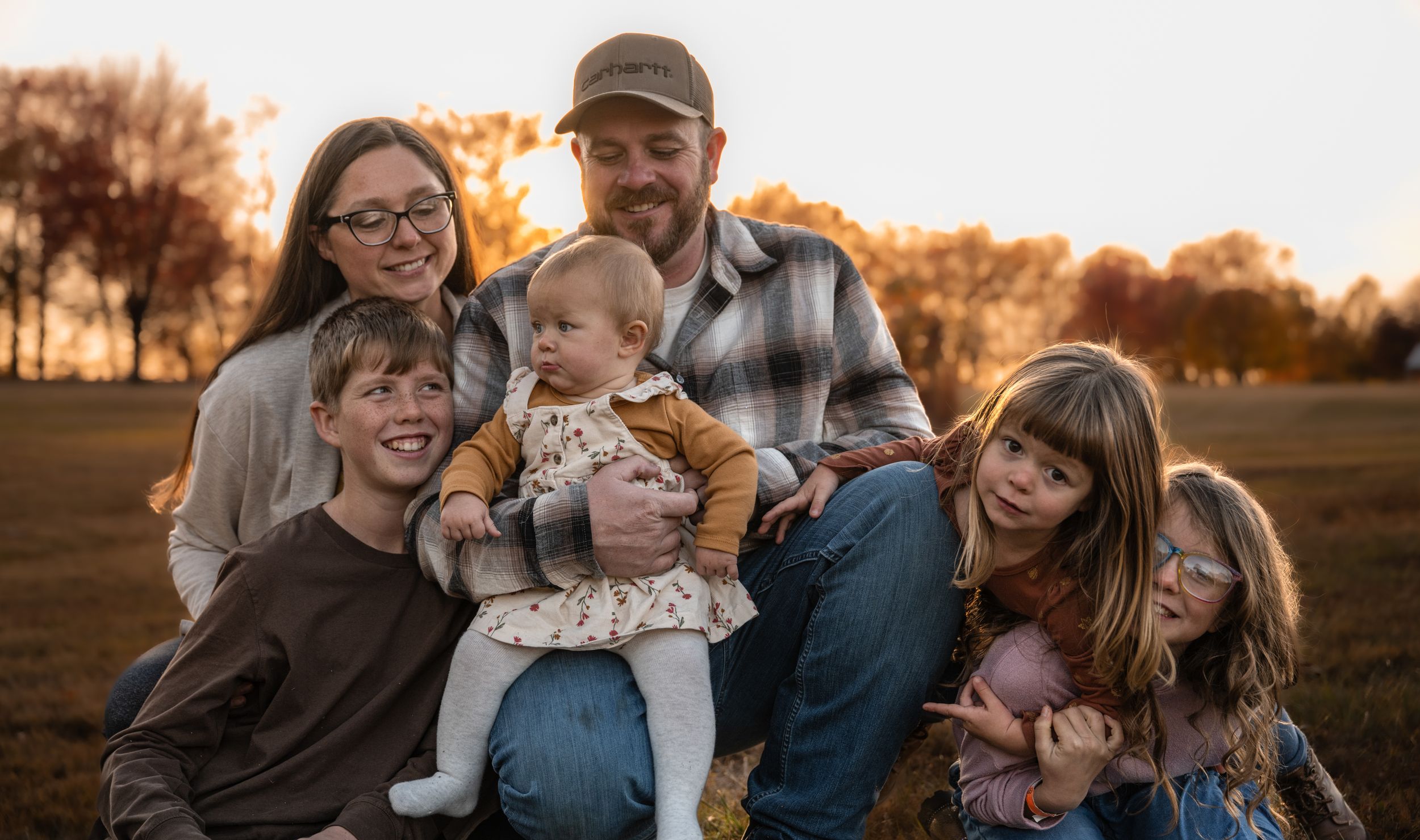 Family enjoying a warm sunset moment together outdoors in casual attire.