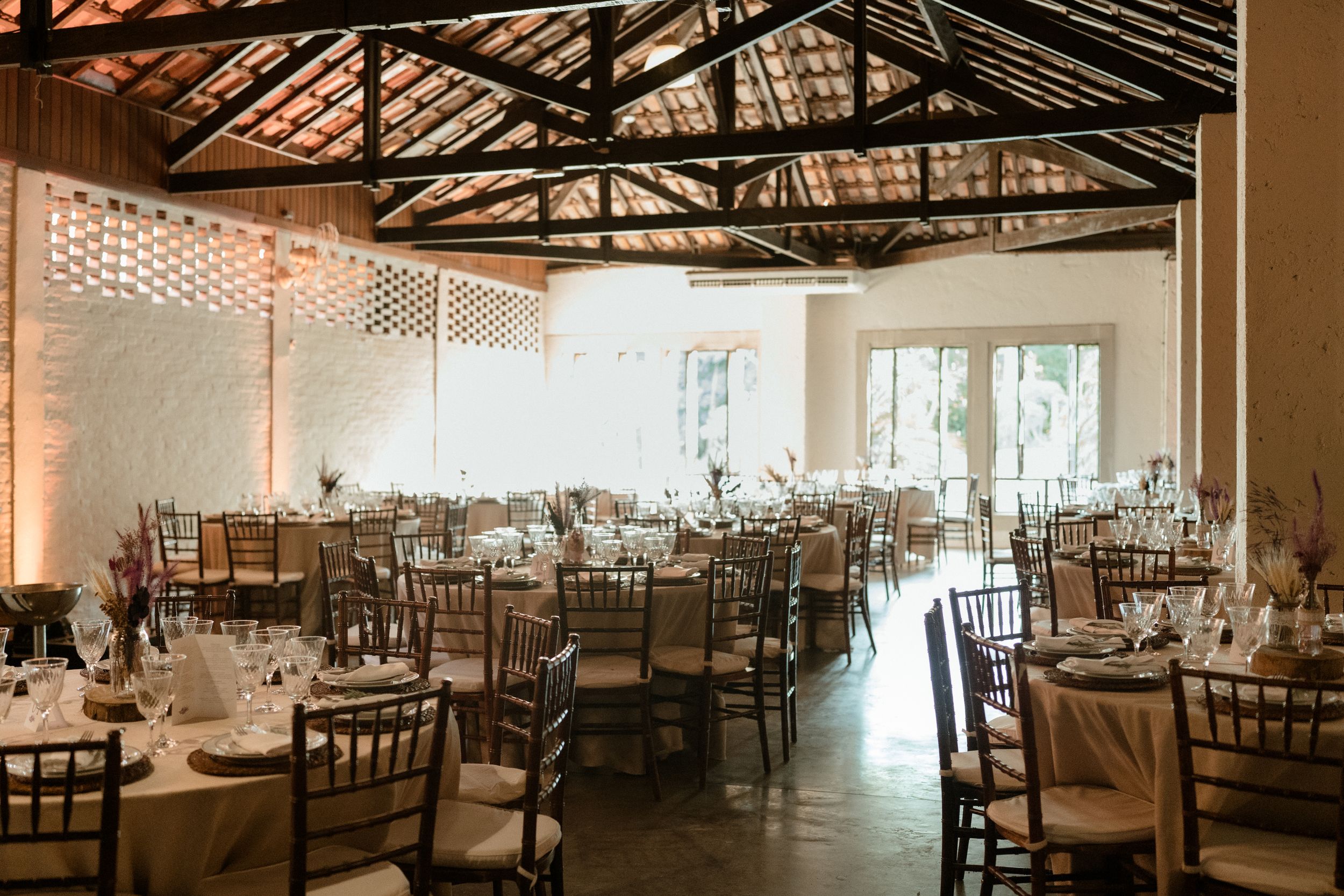 Elegant wedding reception venue with chiavari chairs and exposed beam ceiling.