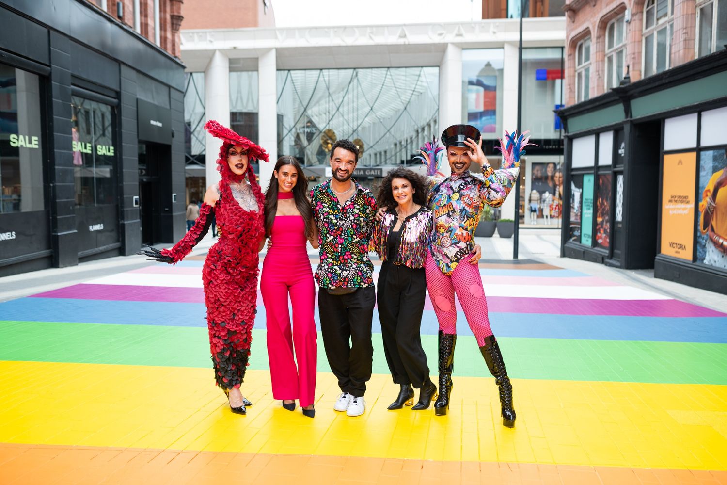 People walking across a colorful rainbow-striped pedestrian area in an urban setting.