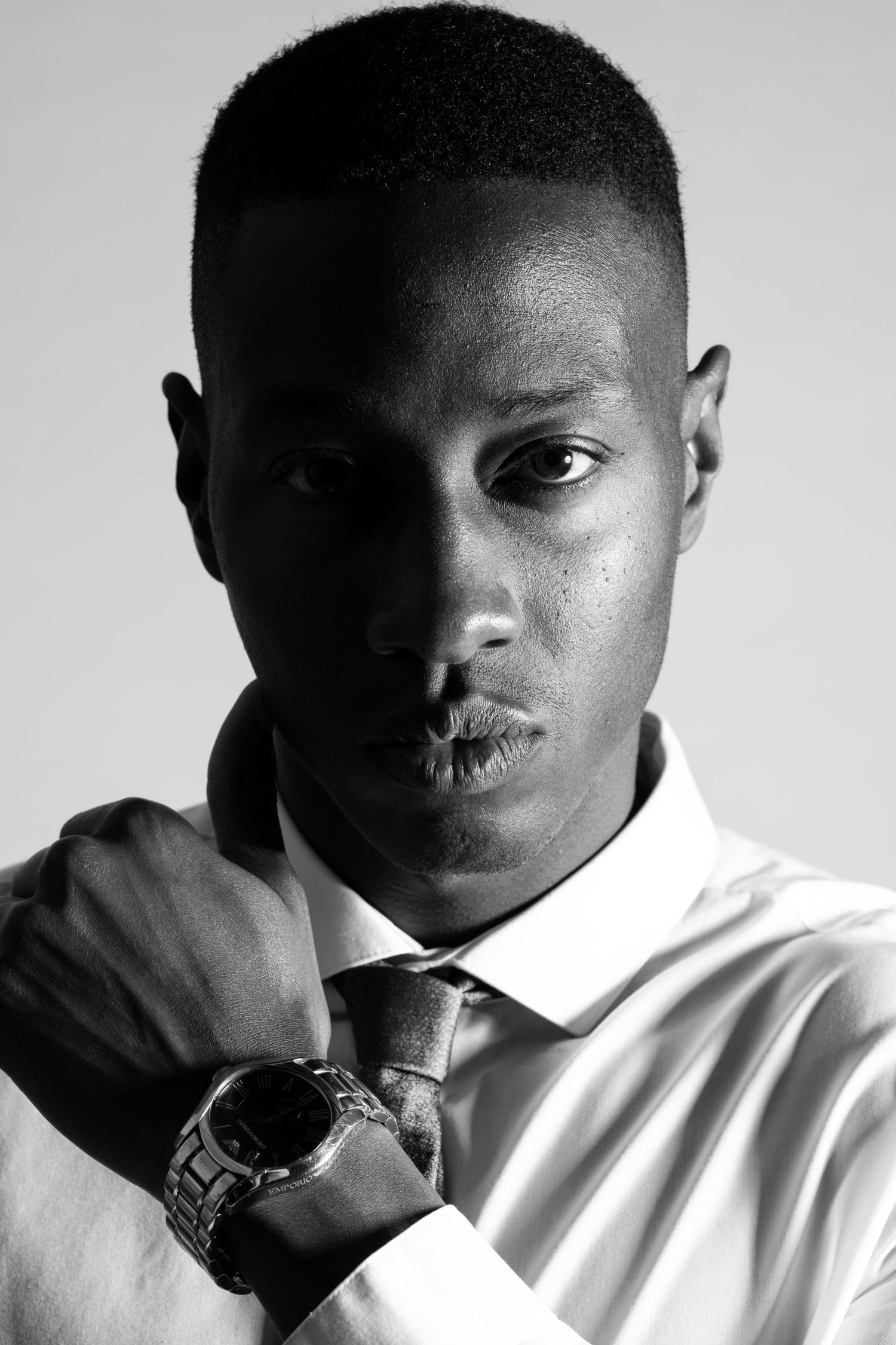 Professional portrait in black and white showing person wearing white shirt and watch.