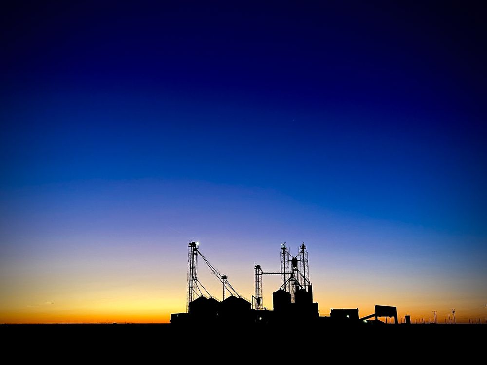 Grain elevator silhouette against vibrant blue and orange sunset sky.