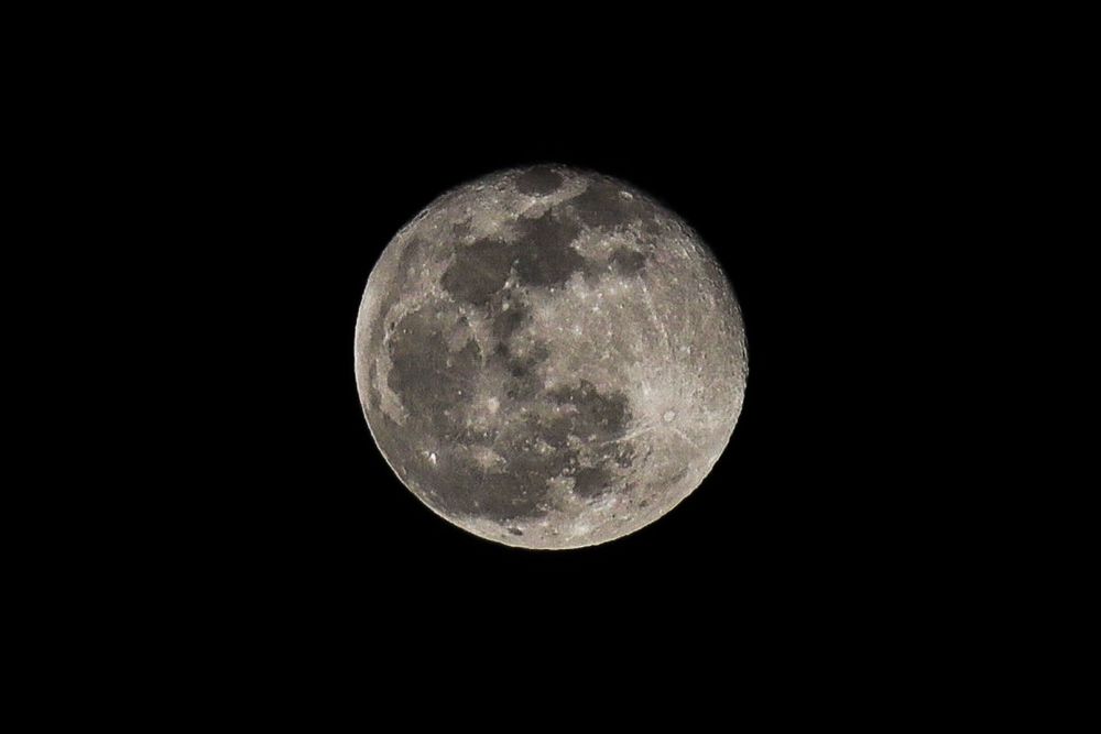 Detailed photograph of a full moon showing lunar surface features against a black sky.