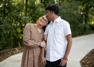 Romantic couple in casual wear sharing tender moment on park pathway.