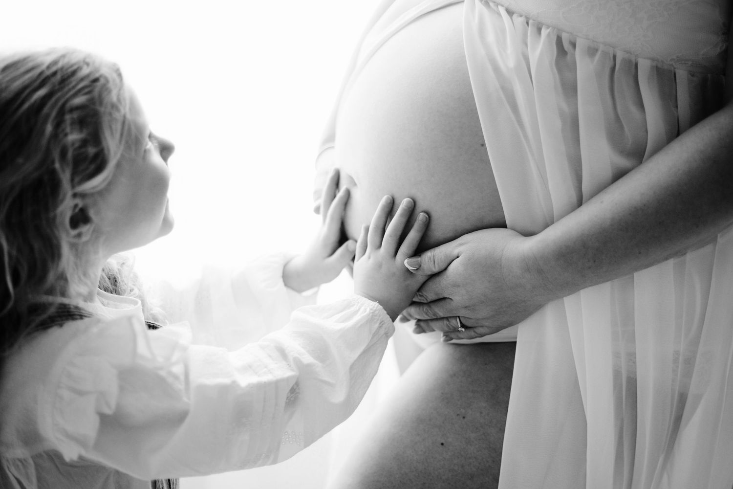 Black and white maternity photo of pregnant woman in cowboy hat posing in studio setting.
