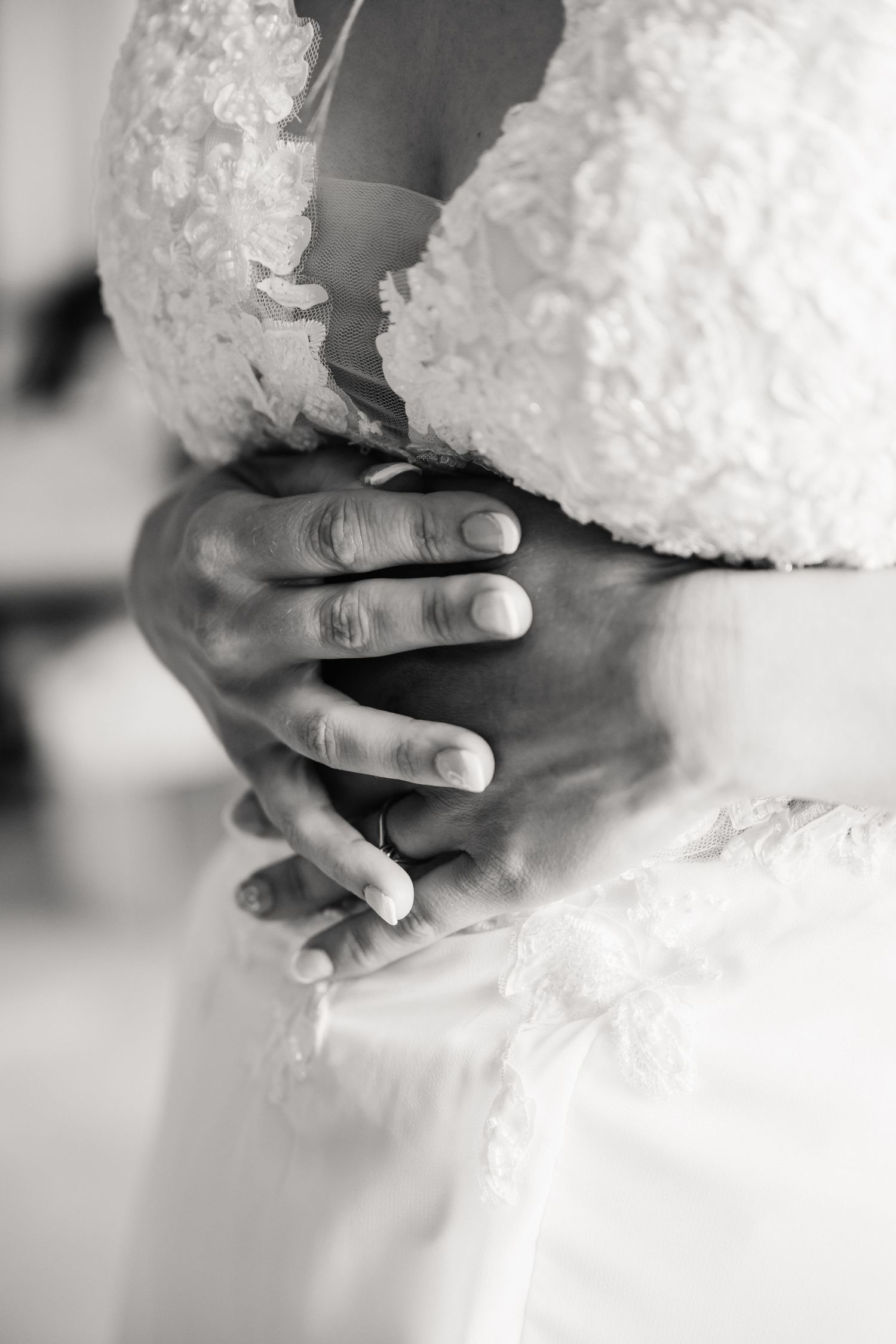 Black and white close-up of groom's hands clasped around bride's lace wedding gown waist at Pennsylvania Castle, Portland Dorset