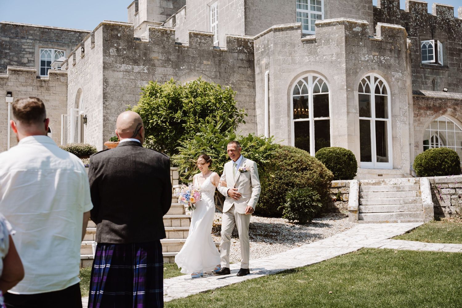 Bride and groom walking outside a stone castle venue on their wedding day at Pennsylvania Castle, Portland Dorset