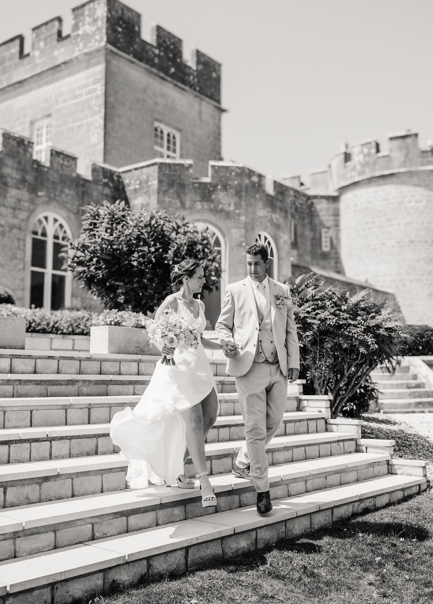 Black and white photo of bride and groom descending castle steps on wedding day at Pennsylvania Castle, Portland Dorset
