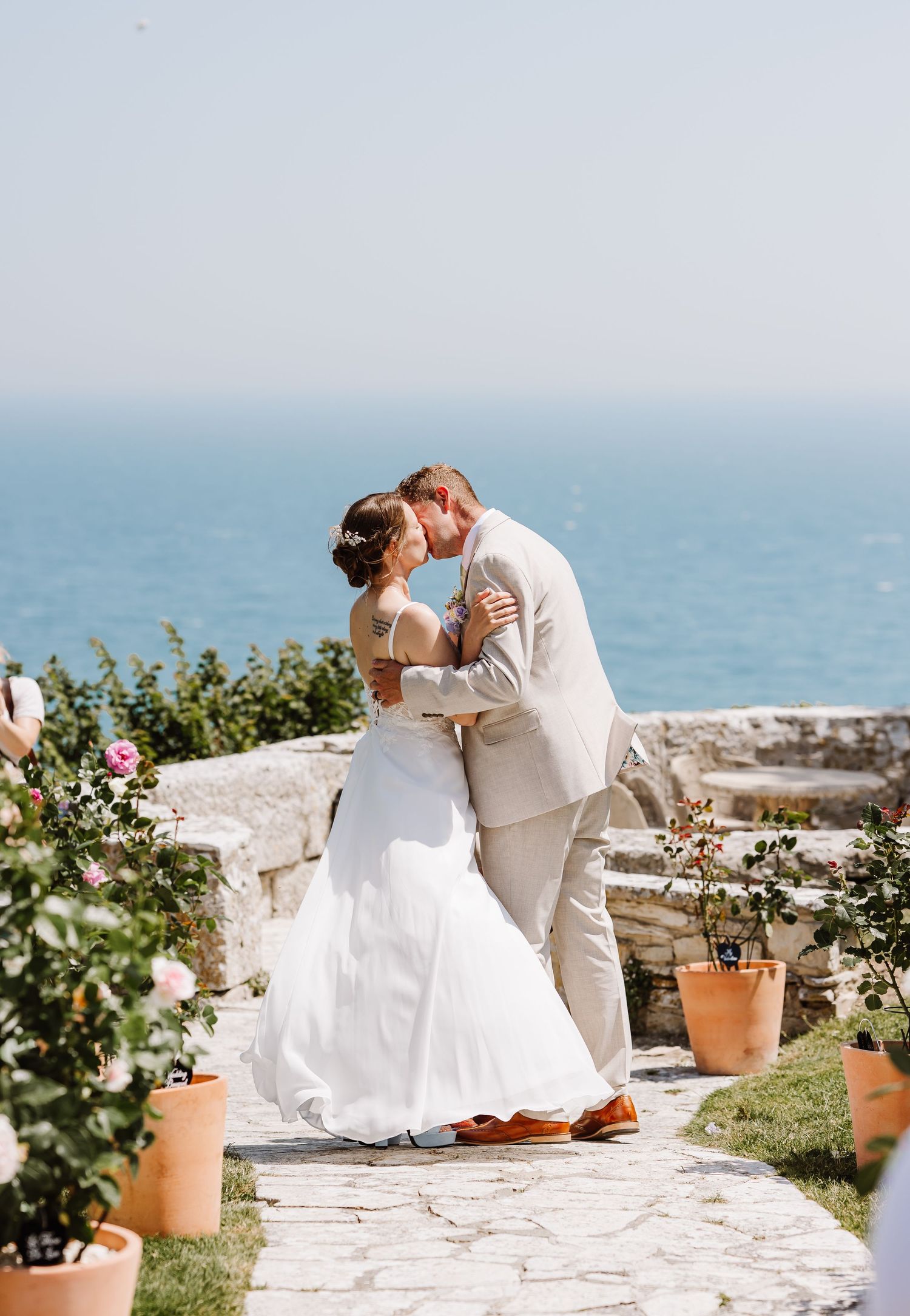 Bride and groom sharing a romantic kiss with the ocean as a stunning backdrop at Pennsylvania Castle, Portland Dorset