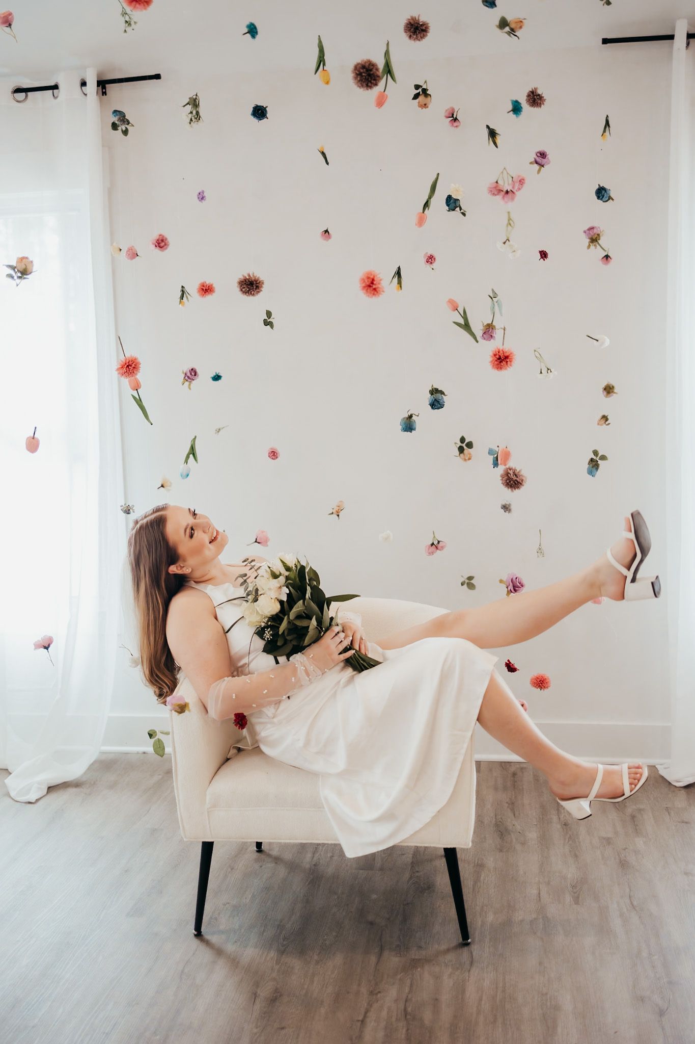 bride is kicking her leg up in a chair surrounded by floating flowers