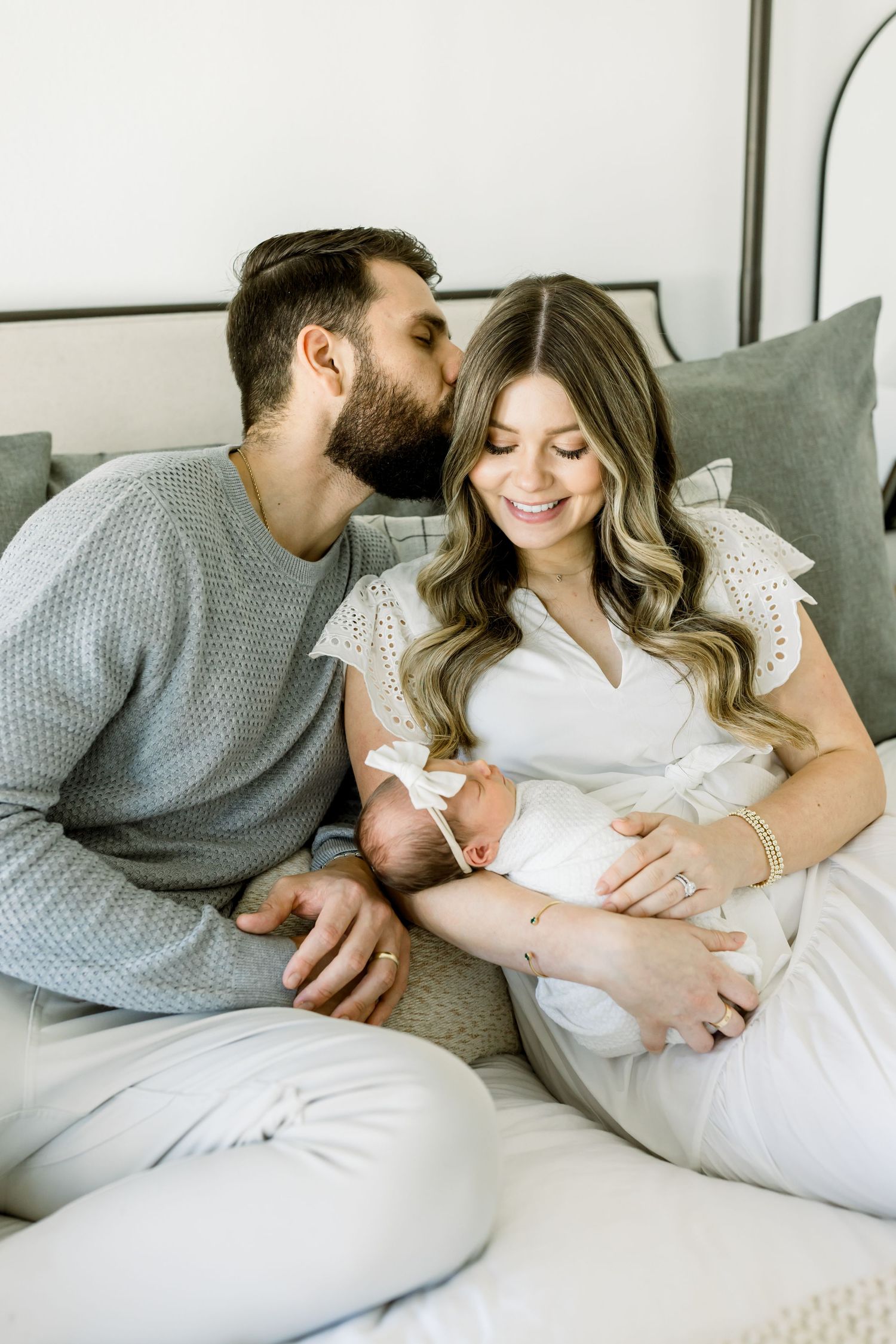 Intimate family moment with newborn baby on grey couch.