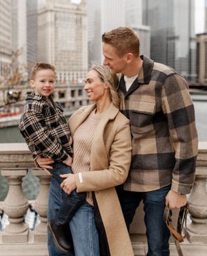 Family poses together against Chicago skyline backdrop on stone balustrade.