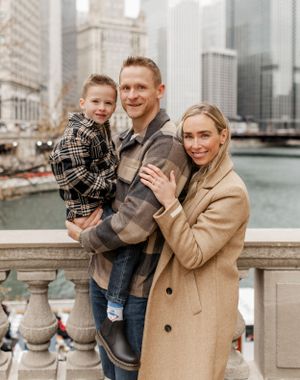 Family portrait taken on stone balustrade overlooking Chicago River and downtown buildings.