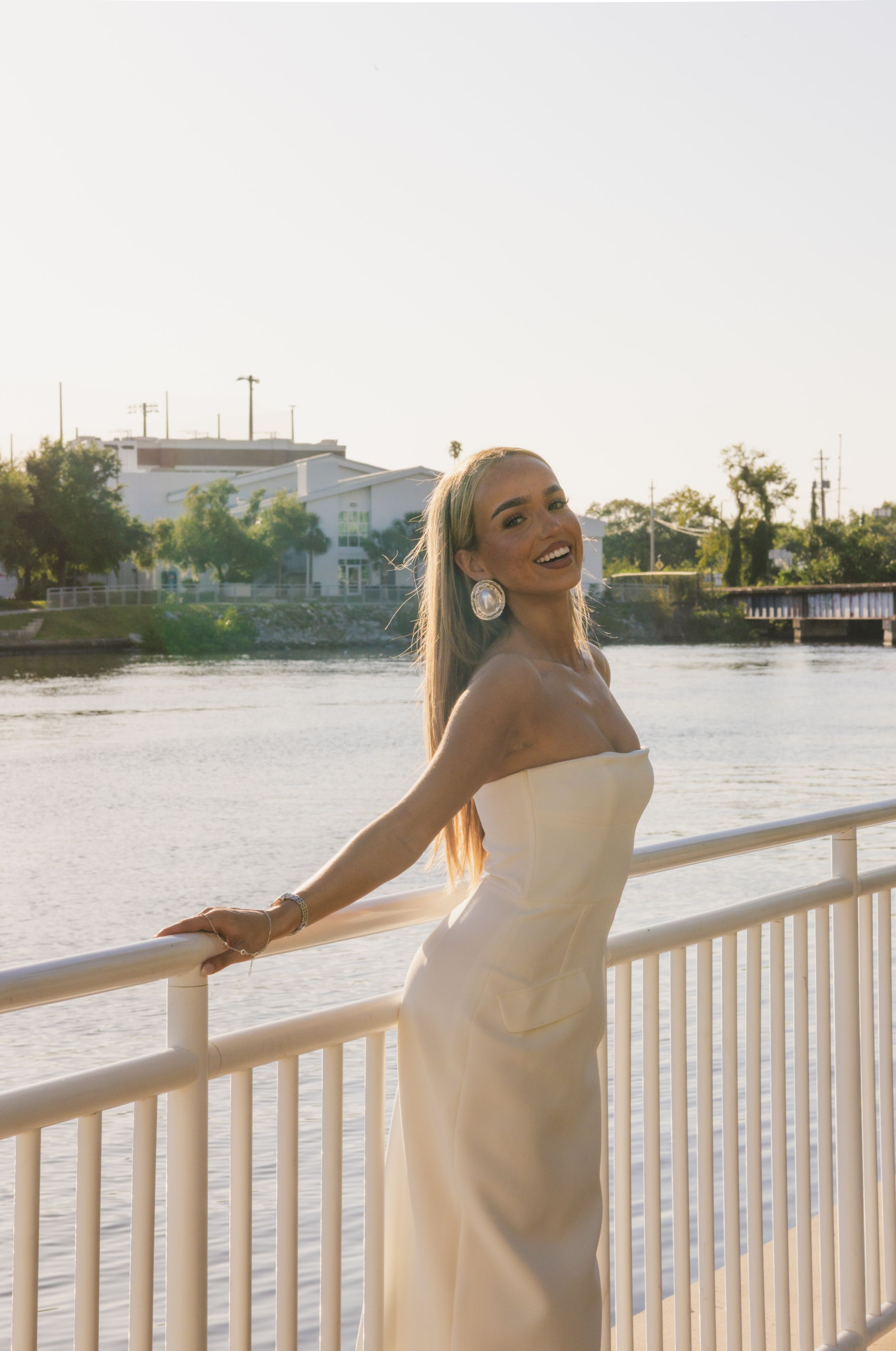 Leaned against the railings of Curtis Hixon park, a girl is smiling at the camera in the glowing sun.