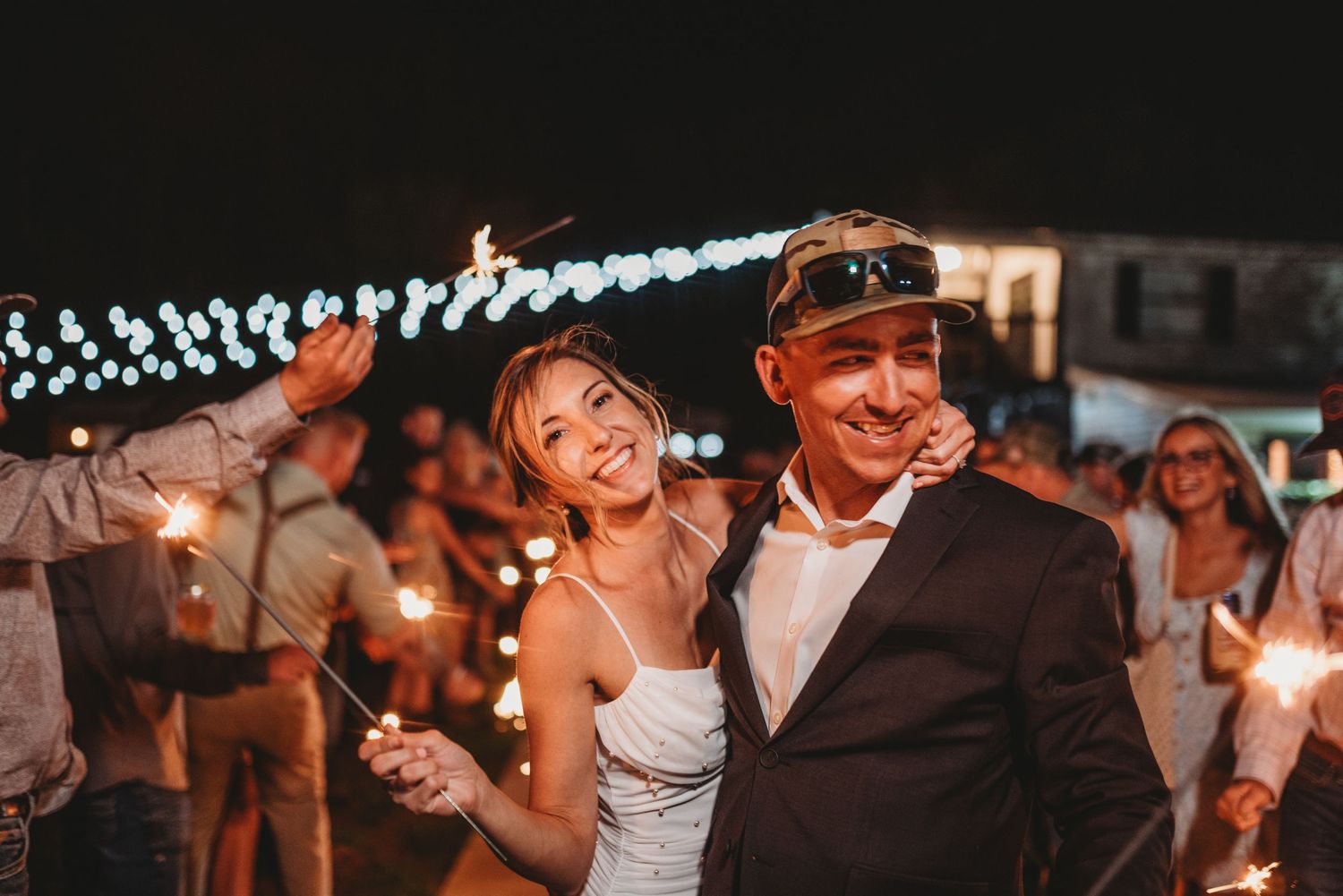 A couple celebrates during their wedding sparkler exit with joyful expressions.