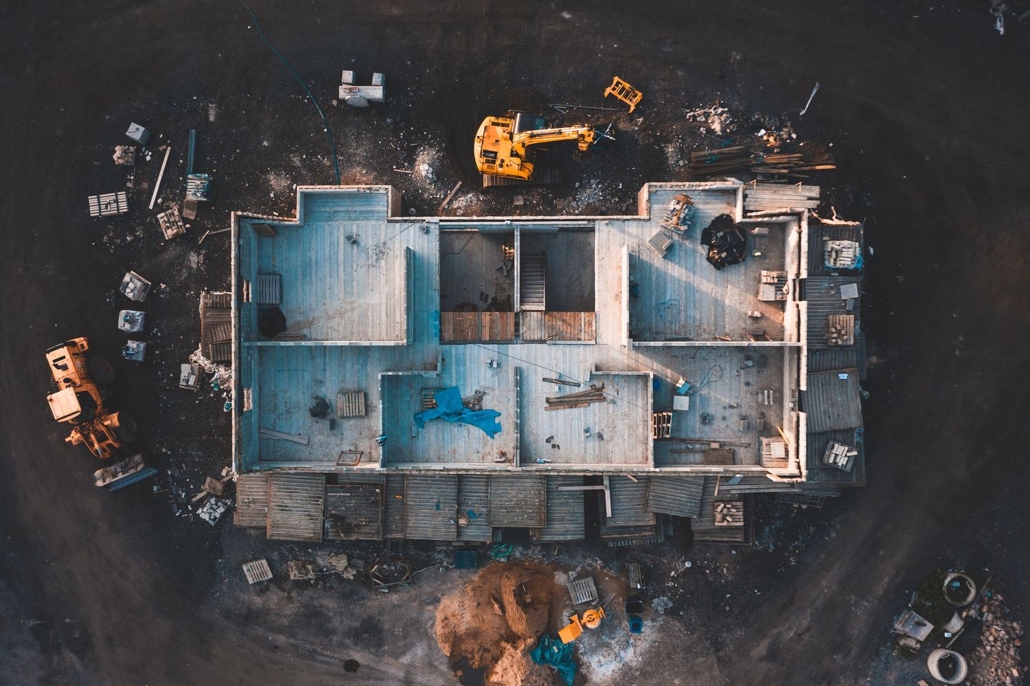 Aerial drone view of building floor plan layout with construction materials scattered around.