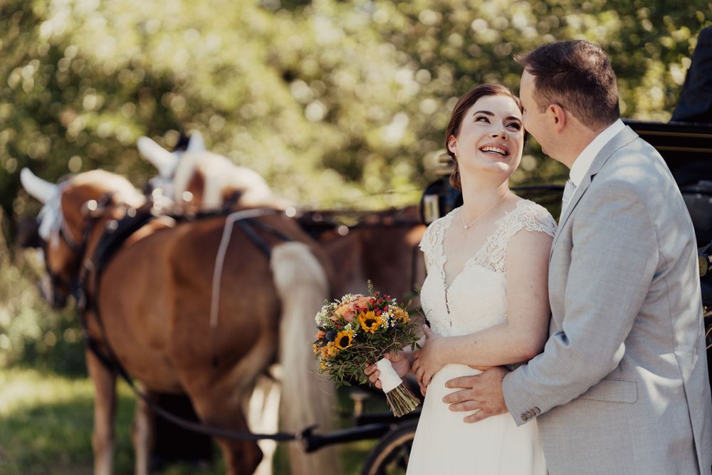 Hochzeitspaar fährt auf einer romantisch geschmückten Pferdekutsche – zeitlose Hochzeitsfotografie in Ettlingen im Vintage-Stil.