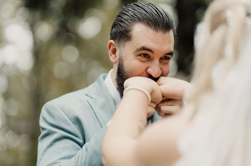 Der Bräutigam küsst liebevoll die Hand der Braut – ein zärtlicher und eleganter Hochzeitsmoment.